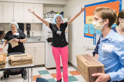 Abigail Miller, R.N., celebrates as Girl Scout cookies are dropped off to her unit. A-Turner Moving donated 20,000 boxes of Girl Scout cookies to UF Health to be distributed to workers across the hospital system during the COVID-19 outbreak. — © UF Health, Photo by Louis Brems