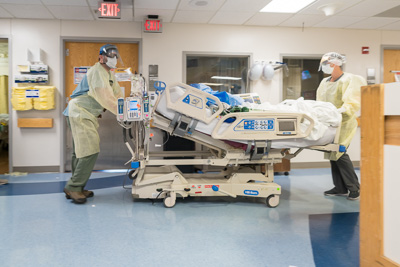 Registered nurses Jay Steiner and Jennifer Brooks transfer a COVID-19 patient from Unit 94 to the COVID ICU at UF Health Shands Hospital after the patient’s symptoms worsened. — © UF Health, Photo by Louis Brems