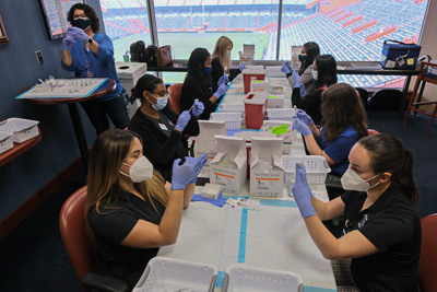 The willingness of everyone on campus to step up and aid in the response to the pandemic for the local community was an amazing thing to bear witness to. This image shows a room full of UF College of Pharmacy students prepping vaccine doses for the public during the first public vaccination events held at UF’s Ben Hill Griffin Stadium. — © University of Florida, Photo by Jesse S. Jones